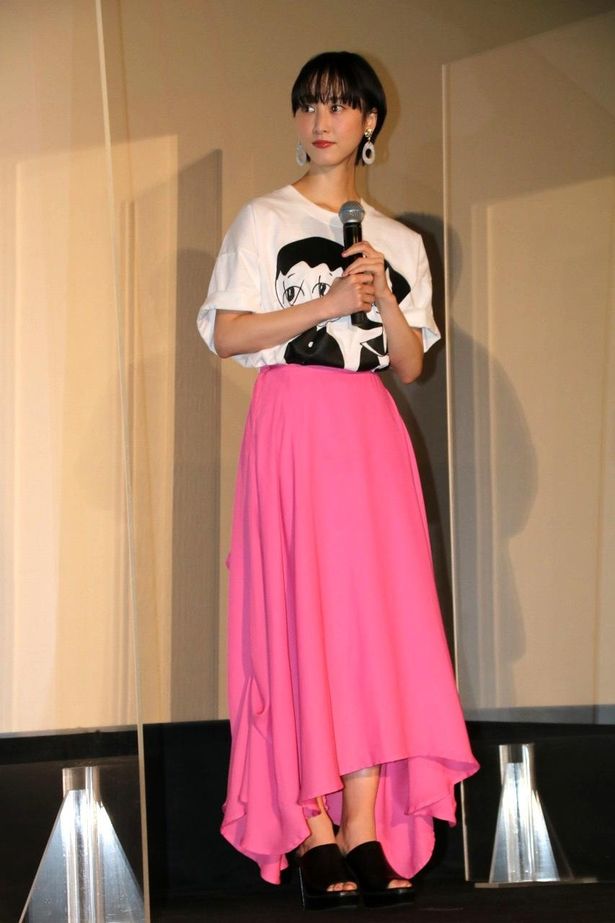 【写真を見る】松井玲奈は「ゾッキ」のTシャツとピンクのスカートをコーディネート