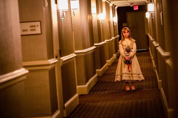 ドレスを着た少女が廊下でポツンと立つ、美しくも不気味なショット