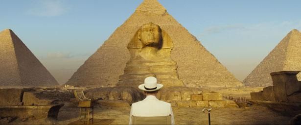 【写真を見る】巨大なピラミッドとスフィンクスを眺めながら優雅にお茶をする名探偵ポアロ
