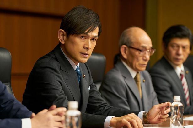 官房長の海原渉、奥には総理大臣の竹上登志雄の姿も