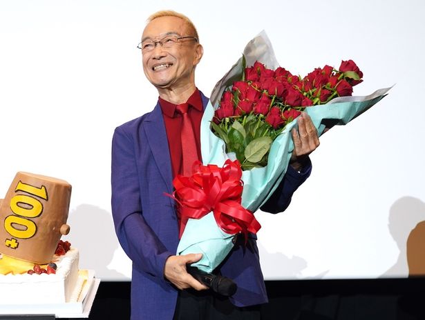 【写真を見る】77本の花束は「ずっしり！」と笑顔の神谷明。声優の道を拓いてくれた先輩たちに感謝する場面も。