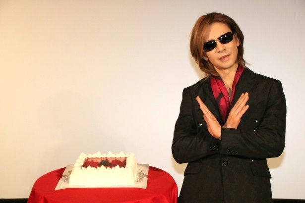 【写真を見る】YOSHIKIがサプライズのバースデーケーキの前でXポーズ