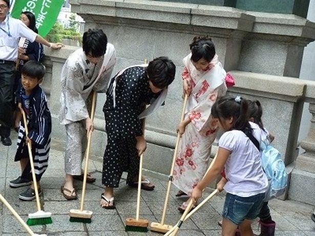 子供たちと一緒にブラシで日本橋を磨くキャストたち