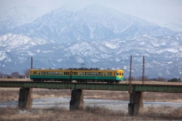 北アルプスの山々を背景に疾走する富山地方鉄道の車両