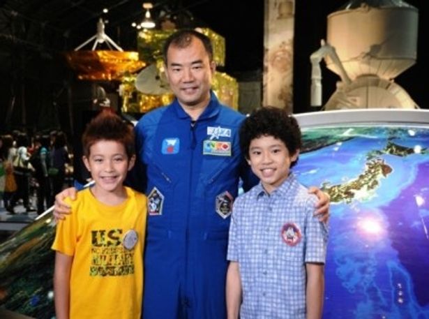 幼いムッタとヒビトの肩を抱き、彼らが憧れる宇宙飛行士として劇中に登場する野口聡一氏(中央)