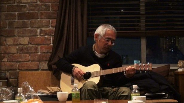 ギターを弾く鈴木プロデューサー