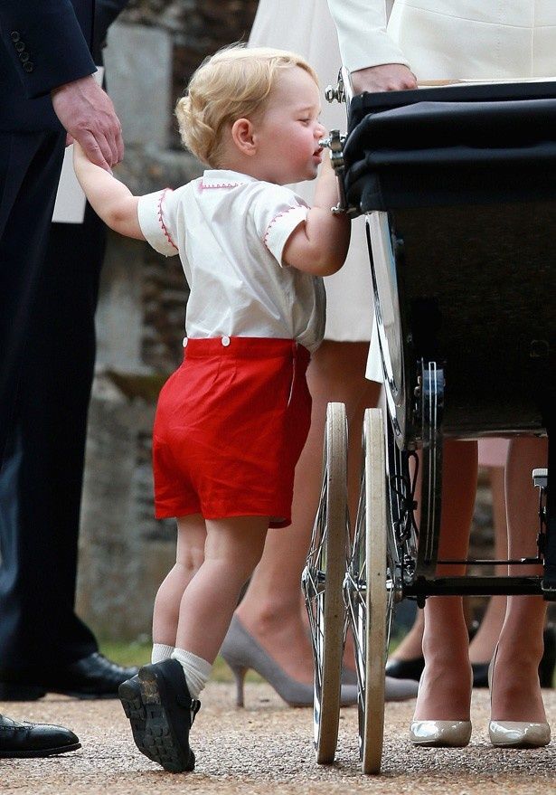 【写真を見る】背伸びをして、妹・シャーロット王女の乳母車を覗きこむジョージ王子