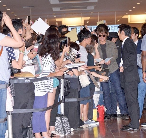 【写真を見る】羽田空港で殺到したファンに笑顔を絶やさずサービスをするトム